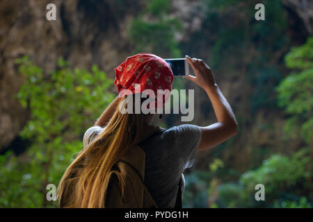 Mädchen touristische macht mobile Photo per Telefon in tropischen Höhle Stockfoto