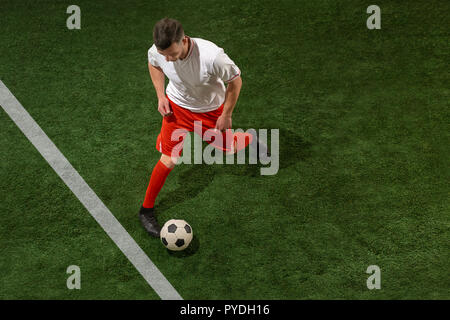 Fußballspieler Bekämpfung für Kugel über grünem Gras Hintergrund. Professionelle Fußball Fußball-Spieler in Bewegung im Studio. Fit springen Mann in Aktion, Springen, Bewegung im Spiel. Stockfoto