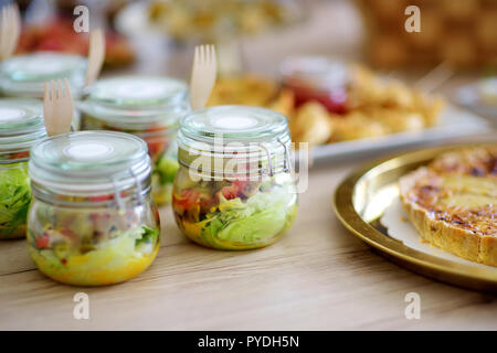 Frisch und lecker Salat serviert in mini Gläser auf einer Party oder Hochzeit. Platten mit sortierten fancy Finger Food Snacks auf ein Ereignis par Stockfoto