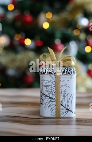 Niedlich und stilvolle Weihnachtsgeschenk. Das Geschenk ist auf einem hölzernen Oberfläche und es ist eine schöne, bunte Weihnachten drei mit viel Dekoration. Stockfoto
