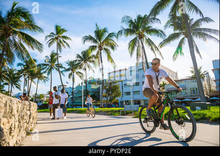 MIAMI - ca. September 2018: Touristen schlendern und Zyklus direkt an der Strandpromenade am Ocean Drive in South Beach. Stockfoto