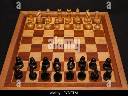 Schwarz und weiß Holz- schachfiguren an Bord mit schwarzem Hintergrund. Stockfoto