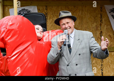 Juni 28, 2015 Glastonbury Festival, England. Ein Mann Sänger gekleidet wie ein 40er Jahre Schlagersänger. Gesang an Glastonbury neben einer Frau als ein rotes Herz gekleidet Stockfoto