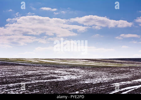 Eines gepflügten Feldes mit Schnee im Frühjahr an einem klaren Tag abgedeckt. Stockfoto