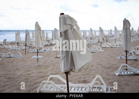 Geschlossen Sonnenschirme in der Wind am Strand, in der Nebensaison, mit keine Personen, die in einem kalten bewölkten Tag, im späten Herbst auf der bulgarischen Küste Stockfoto