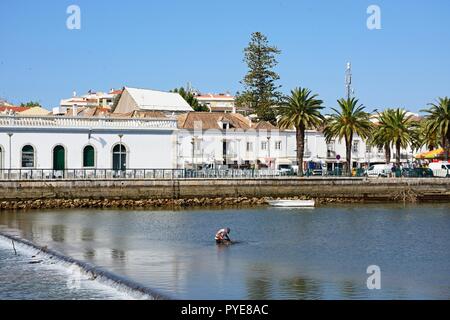 Mann angeln im Fluss Gilao mit Stadt Gebäude an der Rückseite, Tavira, Algarve, Portugal, Europa. Stockfoto