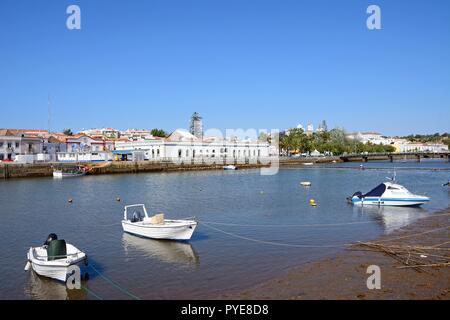 Blick auf den Fluss Gilao in Richtung Stadt Gebäude mit kleinen Fischerbooten im Vordergrund festgemacht, Tavira, Algarve, Portugal, Europa. Stockfoto