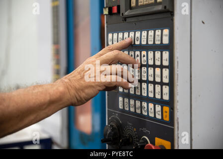 Ein Mitarbeiter drückt die Taste auf dem Bedienfeld des CNC Stockfoto