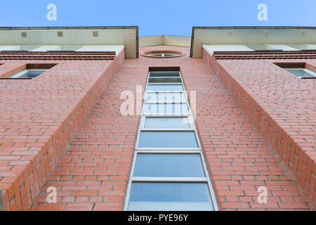 Tageslicht, Blick von unten nach roten Backsteinfassade des modernen Gebäudes. Strahlend blauen Himmel im Hintergrund. Stockfoto