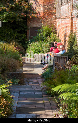 Besucher und die Menschen in einem ummauerten Garten in Bishop's Palace Gardens in Chichester Cathedral Grundstück sitzen an einem sonnigen Tag in West Sussex. Stockfoto