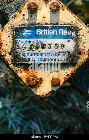 Korrodierte British Rail Identifikation Seriennummernschild auf eine alte rostige Stück von Maschinen in einem Schrottplatz, England, Großbritannien Stockfoto