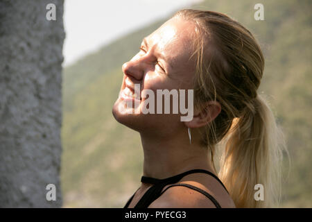 Portrait der junge blonde Frau, blinzeln in die Sonne Stockfoto