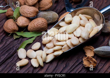 Geschälte Mandeln, mit Schale und mit Haut (almendrucos). Rustikaler Stil, auf Holz- Hintergrund. Stockfoto