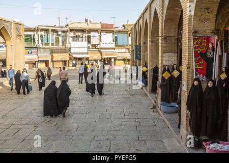 ISFAHAN, IRAN - 20. AUGUST 2016: Frauen in islamischen Bescheidene Kleidung vorbei an den Geschäften der Islamischen outfit Verkäufer schwarzes Kopftuch, Schleier und Stockfoto