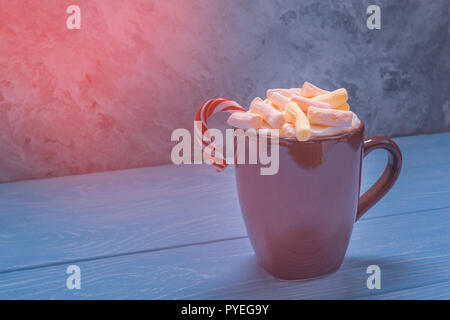 Eine Keramik Tasse braune Farbe ist voller Marshmallows und Weihnachten candy klemmt in der Schale Stockfoto