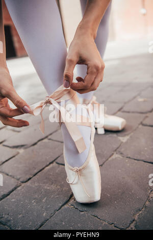 Close-up Teilweise mit Blick auf die junge Ballerina binden pointe Schuh auf der Straße Stockfoto