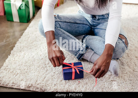 Zugeschnittenes Bild des afrikanischen amerikanischen Frau Eröffnung Geschenk zu Weihnachten zu Hause Stockfoto