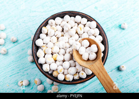 Rohe Hülsenfrüchte Kichererbsen in einer Platte auf einem blauen schäbig Tabelle. Platz für Text Stockfoto