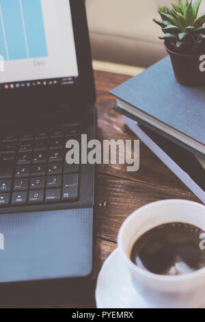 Arbeitsbereich mit Laptop, Kaffee Tasse und Bücher, auf einem Holztisch Stockfoto