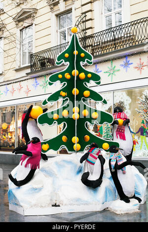 Lemberg, Ukraune - 24. Dezember 2017: Street Installation große Spielzeug Pinguine in der Nähe von Weihnachten Baum mit Orangen eingerichtet. Neue Jahre Ausstellung Stockfoto