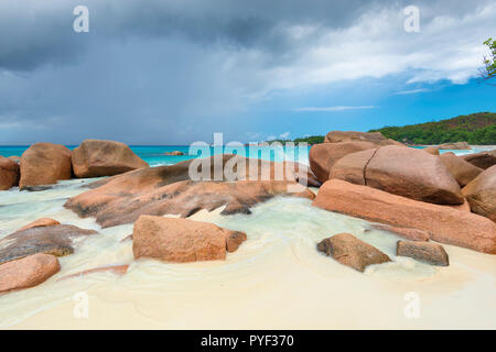 Schöne Steine am Sandstrand und das türkisfarbene Meer in Seychellen Stockfoto