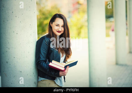 Junge Frau Sie buchen Sie Seiten in der Pause zwischen Hochschule lehren. Pädagogisches Konzept, intelligentes Mädchen in die Kamera schauen. Stockfoto