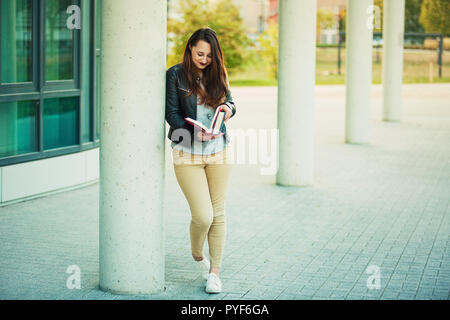 Draußen in voller Länge lifestyle Portrait als junge Frau student surfen Bücher am Bruch innerhalb der Hochschule Campus. Suche nach Wissen, educatio Stockfoto