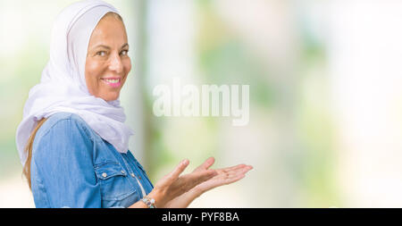 Mittleres Alter östlichen arabischen Frau mit arabischen Hijab über isolierte Hintergrund Einladenden natürlichen lächelnd mit offenen Hand eingeben Stockfoto