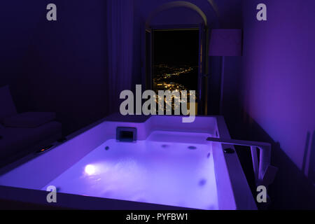 Luxus reisen Santorini urlaub hotel Jacuzzi in farbigen Lichter bei Nacht Blick über die Stadt. Europa resort Reiseziel Urlaub für Flitterwochen. Stockfoto