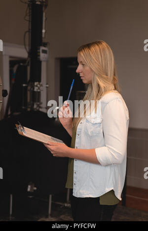Weibliche Arbeitnehmer schriftlich über die Zwischenablage in der Factory Stockfoto