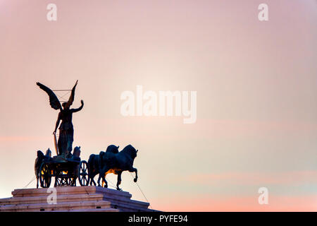 Statue der Göttin Victoria reiten auf Quadriga auf der Oberseite der Denkmal für Vittorio Emanuele II bei Sonnenuntergang, Rom, Italien Stockfoto