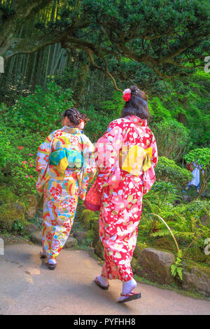 Kamakura, Japan - 23 April, 2017: zwei Frauen, die Japanischen Klassiker rosa Kimonos, die in der grüne Garten von Takera Hokoku-ji Temple von Kamakura, Japan Hanami Frühling Jahreszeit. Vertikale erschossen. Stockfoto