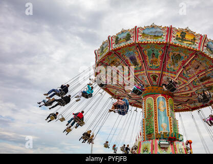 Buntes Karussell an bewölkten Himmel Hintergrund. Oktoberfest, Bayern, Deutschland Stockfoto