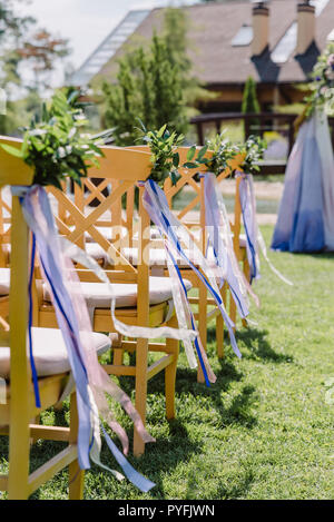 Stühle aus Holz bei einer Hochzeit. Die Stühle mit Knopflöchern und Bänder für Gäste eingerichtet Stockfoto