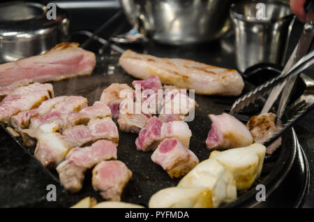 Schweinefleisch kochen auf ein koreanisches Barbeque, eine traditionelle Mahlzeit in einem koreanischen Restaurant. Stockfoto