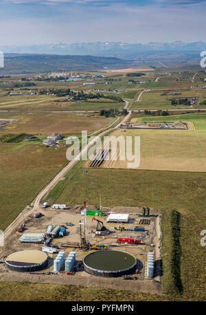 Service rig und Operations bei Versteigerungen in der Nähe von Cochrane, Alberta Kanada mit Rocky Mountains und gas-Anlage im Hintergrund. Stockfoto
