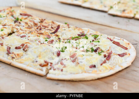 Schwarzwälder Spezialität Flammkuchen genannt, in Süddeutschland und Tarte flambee im Nordosten von Frankreich - traditionellen Richtfest - auf hölzernen Platte Stockfoto