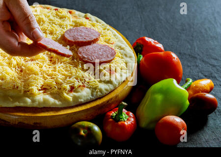 Vorbereitung Bäcker hand Wurst für Pizza Zutaten auf der Pizza Stockfoto