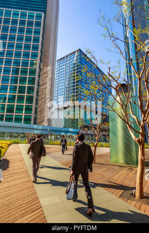 Tokyo, Japan - 20. April 2017: Tokyo städtische Unternehmer Pendler wandern in Shiodome, einem Gebiet mit hohen Wolkenkratzer in Shinbashi Finanzviertel. Yurikamome Monorail in Shiodome entfernt. Vertikaler Stockfoto