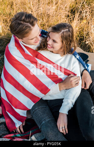 Lächelndes Paar mit der amerikanischen Flagge im Picnic, Independence day Konzept Stockfoto