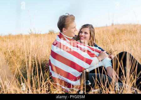 Glückliches Paar mit amerikanischer Flagge ruht auf Gras, Tag der Unabhängigkeit Konzept Stockfoto