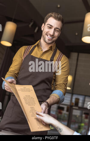 7/8 Schuß von lächelnden Kellner zeigen Menü Liste zu Kunden im Cafe Stockfoto