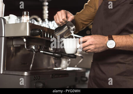 7/8 Schuß von Barista gießen Milch in Kaffee, während der Vorbereitung im Cafe Stockfoto