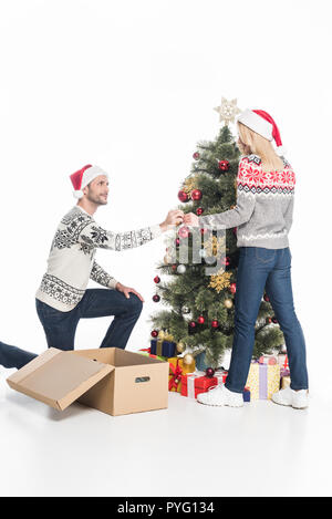 Freundin und Freund in Santa Claus Hüte Dekoration Weihnachtsbaum gemeinsam auf Weiß isoliert Stockfoto