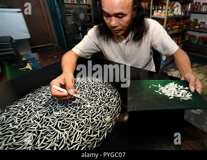 Xiamen, China Fujian Provinz. 26 Okt, 2018. Der chinesische Künstler Lin Hanbing macht Fisch - Knochen Gemälde in Xiamen, im Südosten der chinesischen Provinz Fujian, Okt. 26, 2018. Lin schafft Kunstwerke durch die Vermittlung von Gräten nach mehreren Bearbeitungsschritten. Credit: Zhang Guojun/Xinhua/Alamy leben Nachrichten Stockfoto