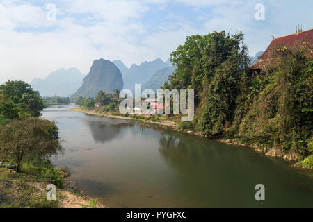 Einen malerischen Blick auf den Fluss Nam Song, Pha Tang Dorf und Kalkstein Berge in der Nähe von Vang Vieng, Vientiane, Laos, Provinz an einem sonnigen Tag. Stockfoto