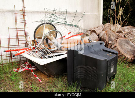Alte Fernseher und den Rest von sperrigen Müll. Alter FERNSEHER weggeworfen neben einer Wand mit einem Stapel von gemischten Müll. in natürlicher Umgebung. Recycling Industrie. Stockfoto