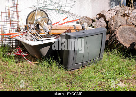 Alte Fernseher und den Rest von sperrigen Müll. Alter FERNSEHER weggeworfen neben einer Wand mit einem Stapel von gemischten Müll. in natürlicher Umgebung. Recycling Industrie. Stockfoto