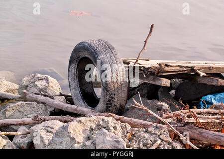 Gebrauchtwagen Reifen links in der Natur. Alte gebrauchte Autoreifen links durch Kosten für Wasser geworfen. Das Problem der Müll am Strand Fluss durch den Menschen - Umweltverschmutzung verursacht. Stockfoto