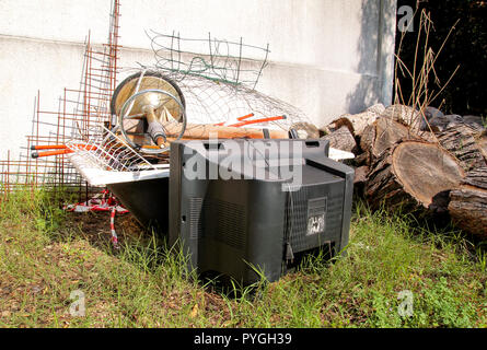 Alte Fernseher und den Rest von sperrigen Müll. Alter FERNSEHER weggeworfen neben einer Wand mit einem Stapel von gemischten Müll. in natürlicher Umgebung. Recycling Industrie. Stockfoto